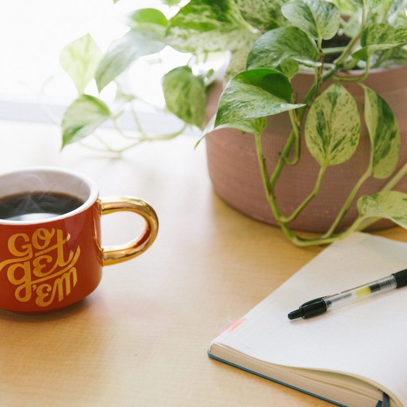 Coffee mug, notebook and pen on a bright desk, ready for birth planning