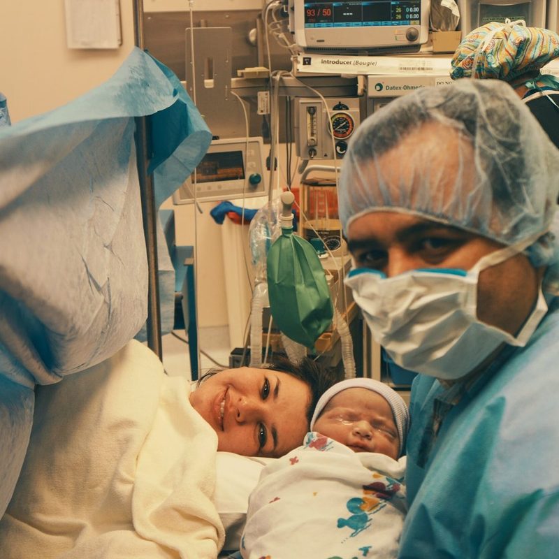 Mother holding her newborn in theatre after a calm caesarean birth