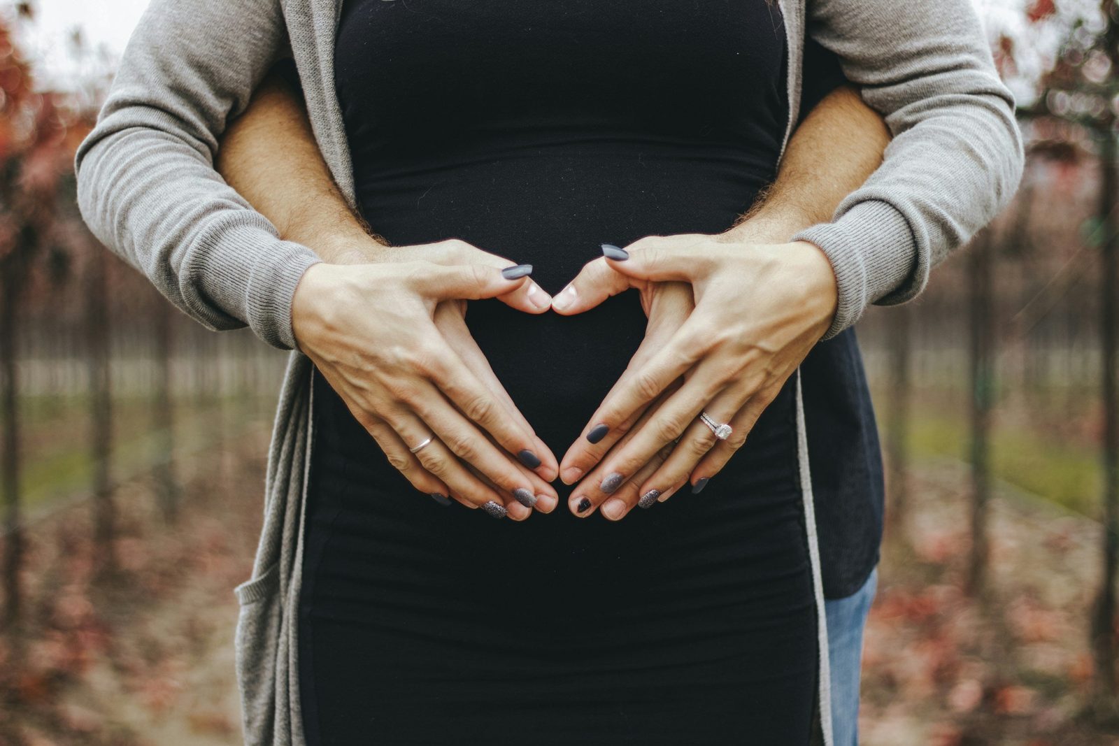 Pregnant woman and partner making a heart shape over the bump