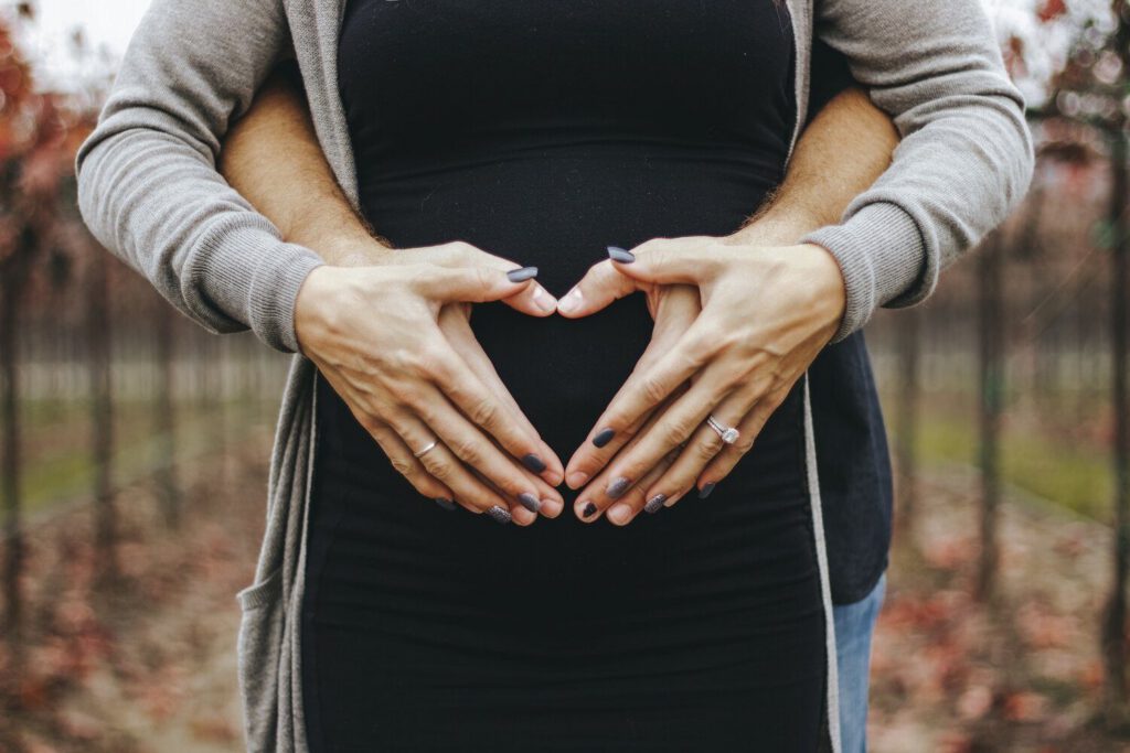 Pregnant couple making a heart shape over the bump